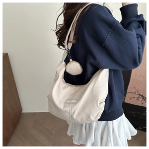 Dettaglio borsa a tracolla a mezzaluna crema con mini pochette e etichetta FANYISSA