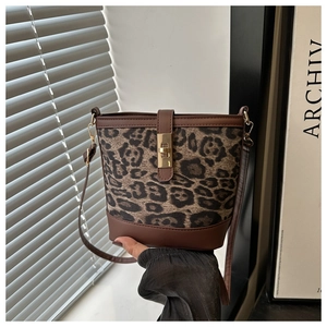 Gros plan du sac seau léopard avec fermoir rotatif doré et garniture en cuir marron