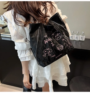 Detail of black tote bag with pink cat graffiti and long silver zipper on wrinkled leather