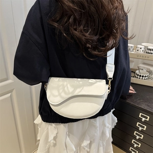 Classic white saddle bag with wide strap and asymmetric flap shown on a model