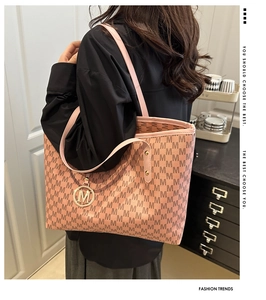 Detail of pink monogram tote bag featuring a gold M charm and elegant shoulder straps