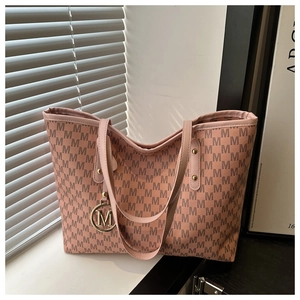 Detail of pink tote bag with repeating M patterns and golden letter pendant charm