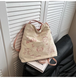 Detail of canvas tote bag with pink straps and cute red cartoon prints on white background