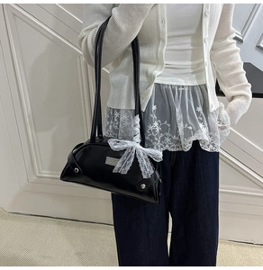 Detail showing the black PU leather handbag with elegant white lace bow and silver logo