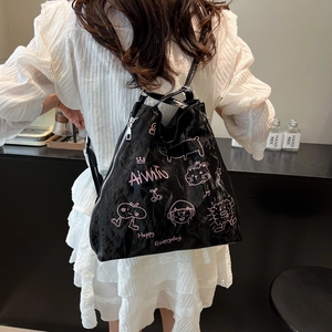 Minimalist black printed backpack with pink cartoon cat pattern for women in a cafe setting