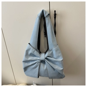 Détail du sac hobo en jean bleu clair avec un grand nœud et une texture solide