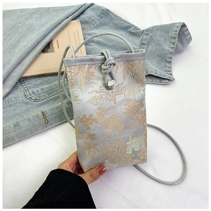 Detailed embroidery of gold landscape patterns on a mini blue silk crossbody phone bag