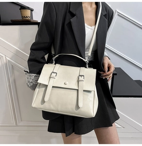 Detail showing off-white PU leather messenger bag with flap closure and silver buckles