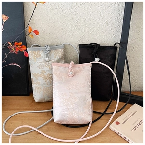 Detailed close-up of three brocade mini crossbody bags with traditional garden embroidery