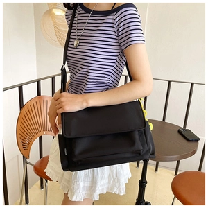 Vue détaillée du sac messager en nylon noir avec bandoulière réglable et étiquette tissée