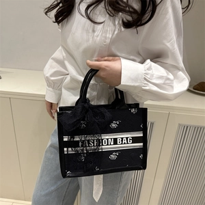 Large black tote bag with white rose pattern, stripe logo, and lace bow decoration