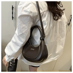 Detail einer dunkelbraunen sichelförmigen Schultertasche mit FASHION-Schriftzug