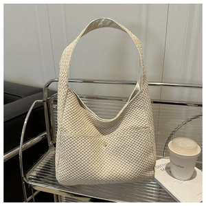 Elegante borsa hobo intrecciata beige con tazza di caffè e libri su scaffale in metallo