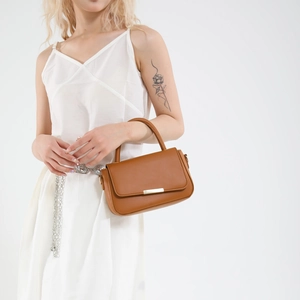 Minimalist brown faux leather crossbody square bag with gold buckle on a white dress model