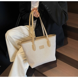 Detail of canvas tote bag with brown faux leather trim and long shoulder handles
