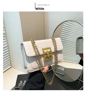 Detalle de bolso blanco con textura de cocodrilo, cadena dorada y cierre geométrico chic