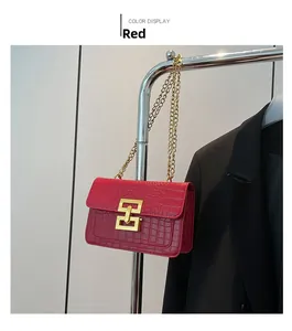 Detalle de un bolso rojo con grabado de cocodrilo y cierre de hebilla de metal dorado