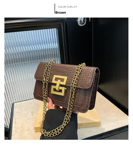 Detalle de un bolso bandolera marrón con diseño de cocodrilo, cadena dorada y cierre