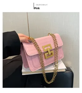 Detalle de un bolso pequeño rosa con relieve de cocodrilo y cadena metálica dorada