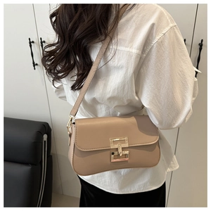 Detailed view of beige crossbody bag with premium gold metal clasp on a leather shoulder bag