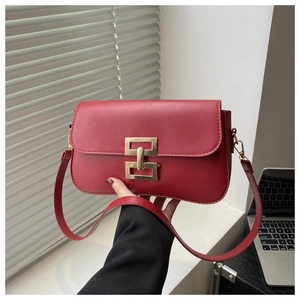 Detail of red leather shoulder bag with gold metal interlocking buckle and flap closure