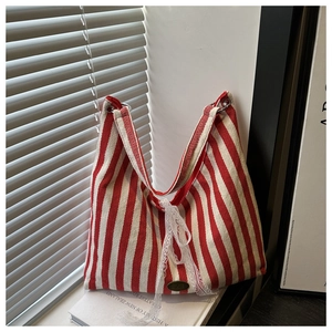 Detail of red and white striped canvas tote with lace bow and handmade metal plate