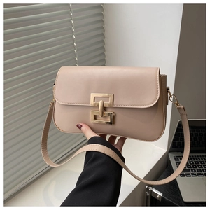Detail of beige square shoulder bag featuring a modern gold geometric metal buckle closure