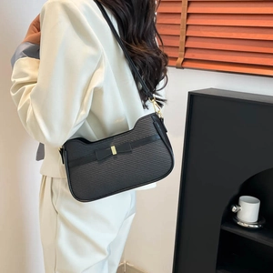 Chic sac sous le bras en sergé noir avec nœud en cuir et détail doré porté par un modèle