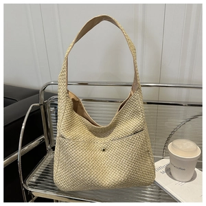Dettaglio borsa tote in paglia intrecciata con ampia tracolla e fibbia in metallo dorato