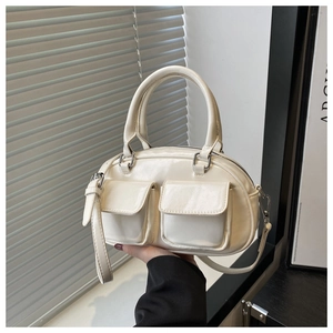 Detail view of a creamy white baguette bag with double front flap pockets and silver hardware
