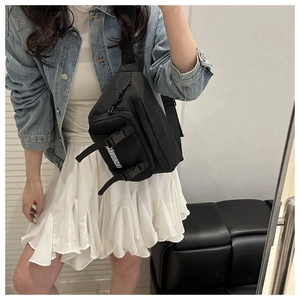 Close-up of black nylon crossbody bag featuring white fashionable text and adjustable buckle
