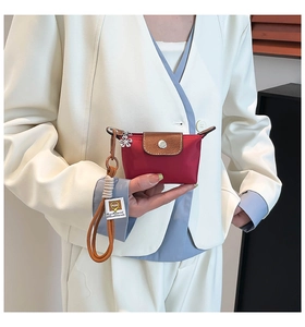 Detailopname van rode nylon mini-tas met bruine lederen flap en decoratieve hanger