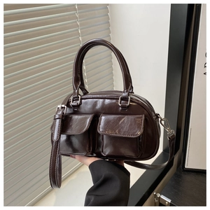 Close-up of shiny chocolate brown baguette bag with dual front pockets and glossy leather