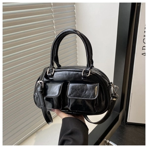 Detail of black glossy leather Boston bag with functional pockets and silver zippers