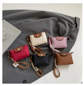 Detailweergave van mini nylon tassen in rood, beige, roze, zwart en bruin met koordgrepen