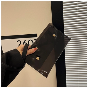 Detail einer transparenten schwarzen PVC-Umschlagtasche mit goldenen Druckknöpfen