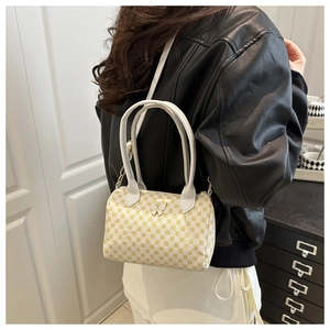 Détail du sac Boston blanc à pois jaunes et breloque papillon argentée sur le côté