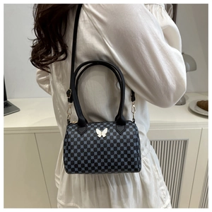 Gros plan du sac Boston avec motifs géométriques bleus et breloque papillon élégante