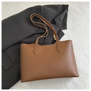 Detail of a brown leather tote bag with a decorative floral twilly on the handle