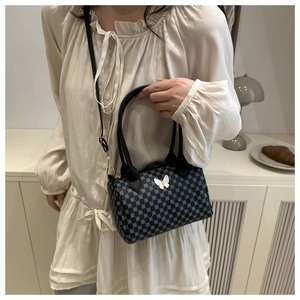 Détail d'un sac cylindre rétro avec motif à pois bleus et un papillon blanc en relief 3D