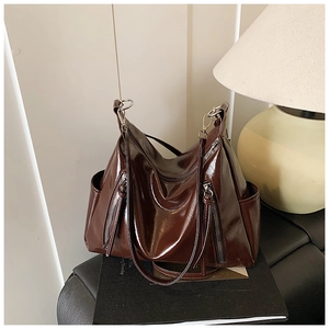 Detail of high-shine oil wax leather surface and silver zipper pockets on tote bag