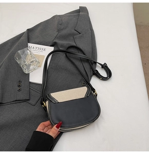 Gros plan détaillé du sac selle en cuir et toile contrastés sur un blazer gris chic