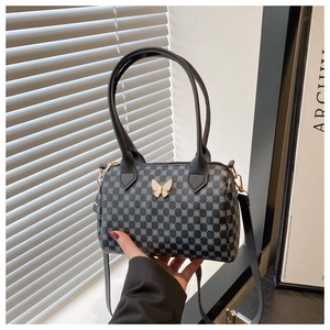 Détail du sac polochon gris avec motifs géométriques et fermoir papillon doré élégant