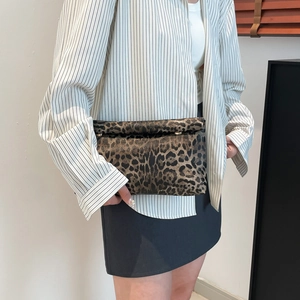 Fashionable leopard print clutch bag with flap closure held by model in casual outfit