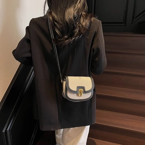 Sacoche vintage en toile beige et cuir noir portée avec un blazer noir élégant