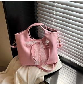 Detailed shot of pink bucket bag featuring a large white lace bow and golden hardware