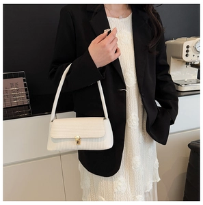 Close-up of white textured leather shoulder bag with elegant gold buckle and strap details