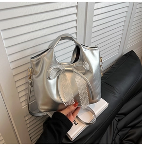 Detail of silver bow handbag with delicate white lace trim and metallic leather finish