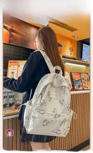 Detailed side view of white butterfly backpack with adjustable straps and side pockets