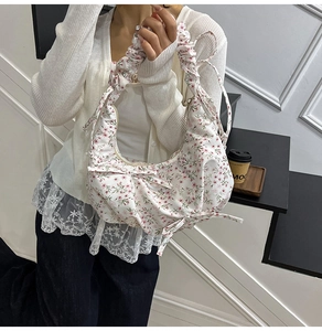 Detail of floral tote bag with bow accents and pleated strap in creamy white fabric